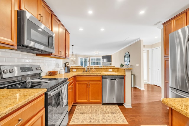 kitchen featuring crown molding, decorative backsplash, a peninsula, light wood-type flooring, and appliances with stainless steel finishes