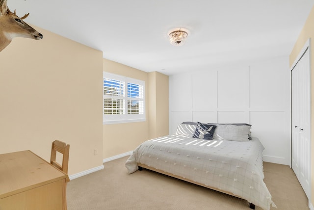 bedroom featuring light colored carpet, baseboards, and a closet