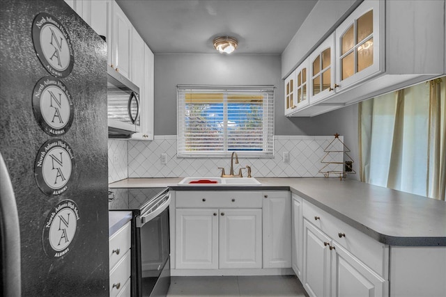 kitchen with glass insert cabinets, white cabinetry, a sink, backsplash, and stainless steel appliances