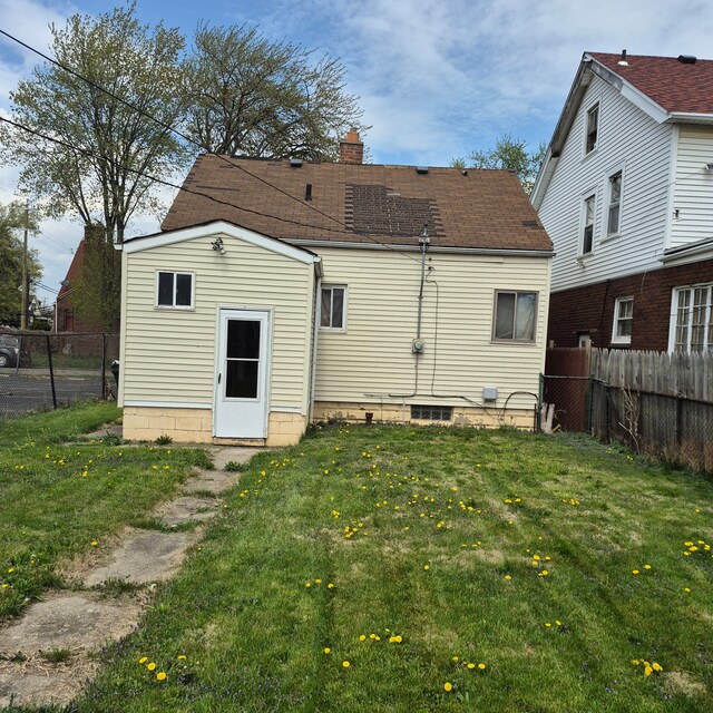 back of property featuring fence, a yard, and a chimney