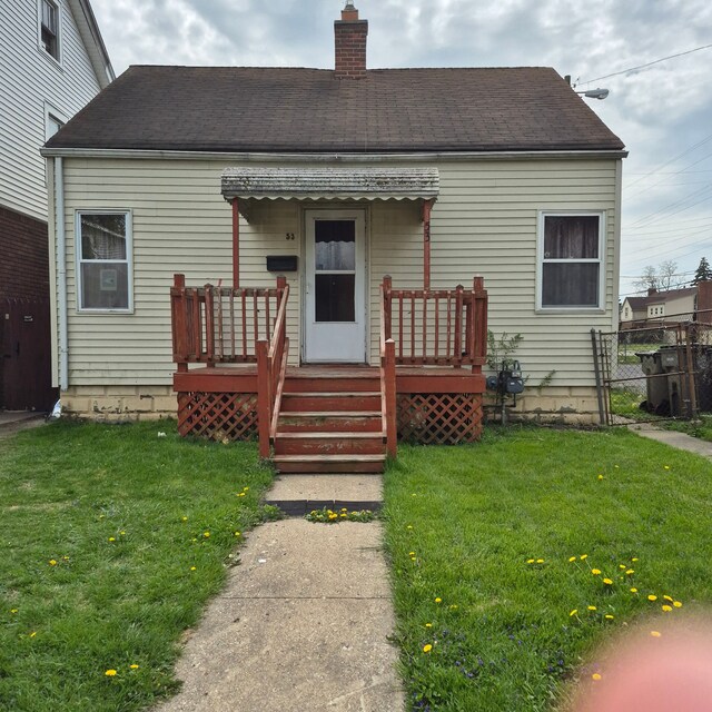 rear view of house featuring a lawn, fence, a chimney, and a deck