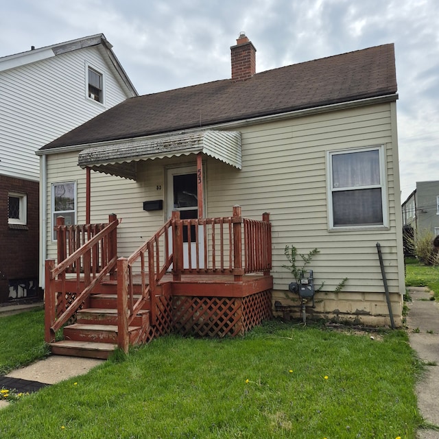 rear view of house with a chimney, a yard, and a deck