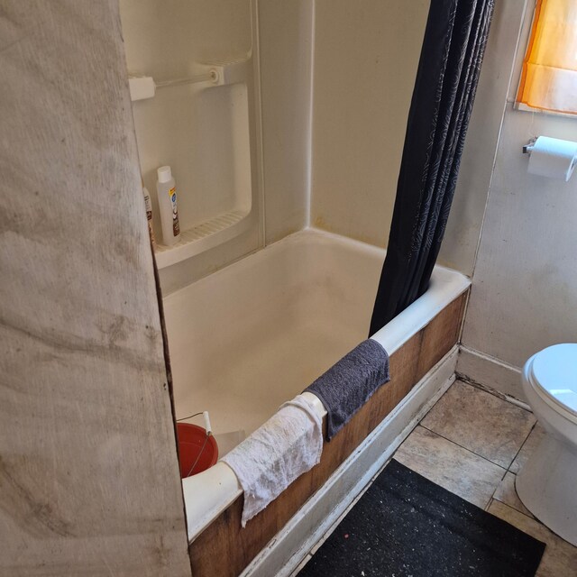 full bath featuring tile patterned floors, baseboards, shower / bath combo with shower curtain, and toilet