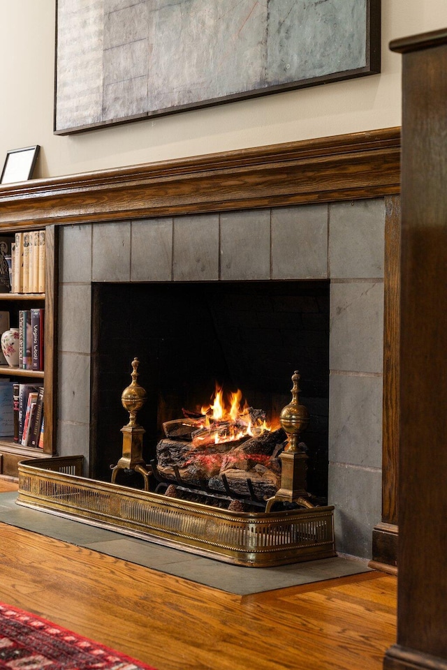 interior details featuring a tiled fireplace and wood finished floors