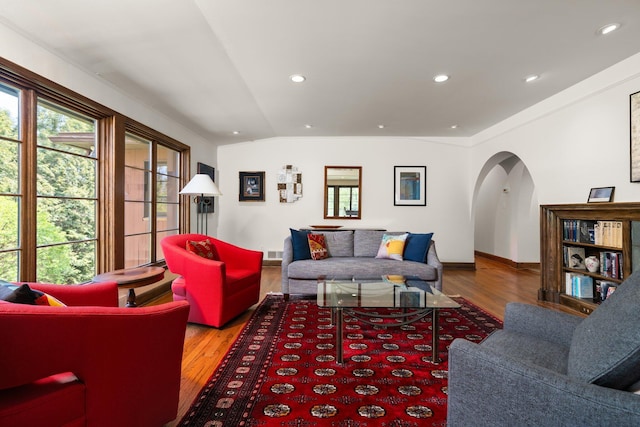 living room with visible vents, arched walkways, wood finished floors, and a healthy amount of sunlight