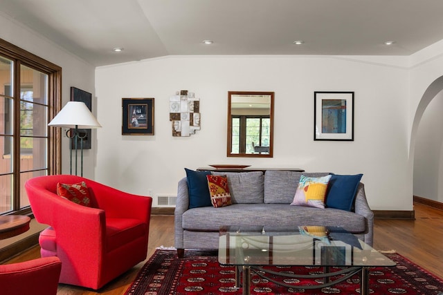 living area featuring arched walkways, vaulted ceiling, plenty of natural light, and visible vents