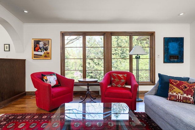 living area featuring crown molding, arched walkways, wood finished floors, baseboards, and recessed lighting