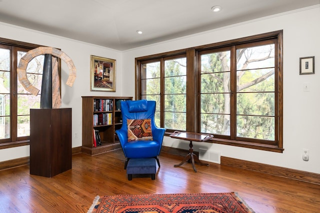 living area with baseboards, visible vents, and wood finished floors