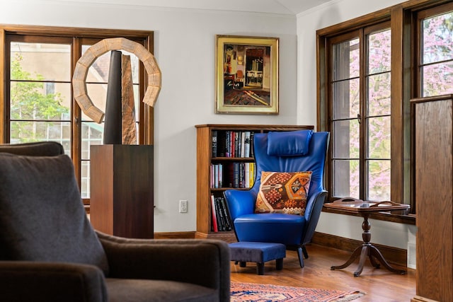 sitting room featuring plenty of natural light, ornamental molding, and wood finished floors