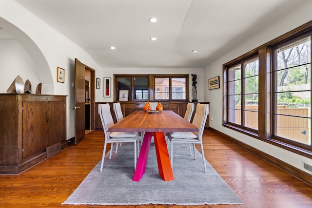 dining area with arched walkways, recessed lighting, baseboards, wood finished floors, and visible vents