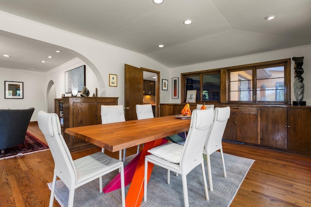 dining space featuring recessed lighting, arched walkways, wood finished floors, and vaulted ceiling