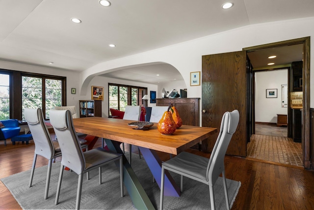 dining space with arched walkways, recessed lighting, and wood finished floors