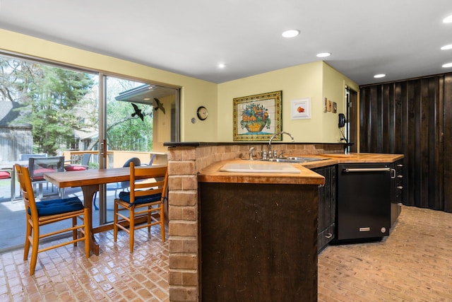 kitchen featuring recessed lighting, brick floor, tasteful backsplash, a sink, and dishwasher