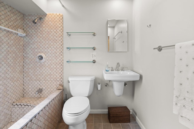 bathroom with toilet, a tile shower, and tile patterned flooring