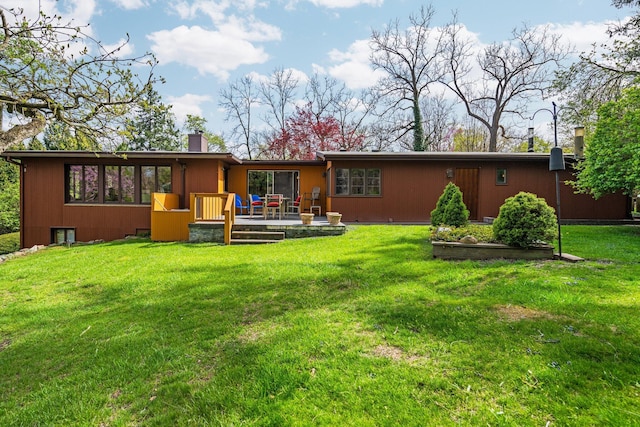 back of property with a lawn, a chimney, and a deck