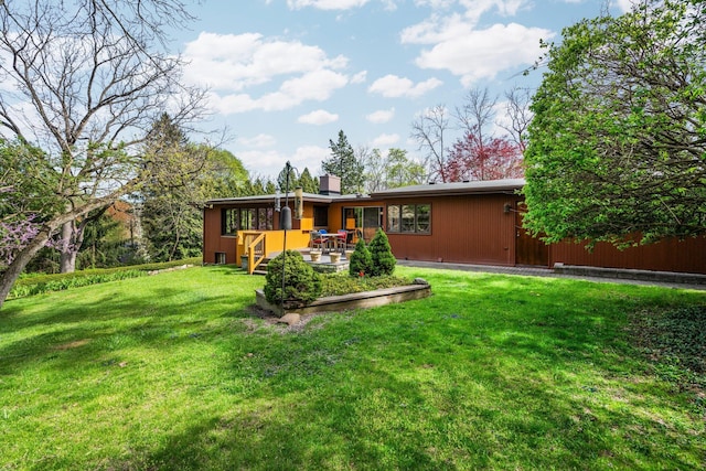 rear view of house with a lawn, a patio, and a chimney