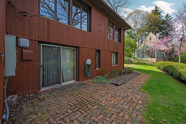 view of exterior entry with a lawn and a patio