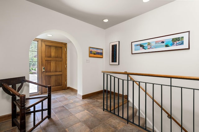 hall with arched walkways, baseboards, stone finish floor, and recessed lighting