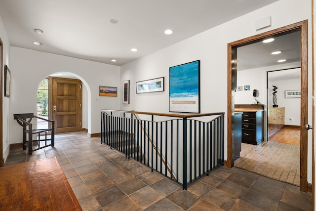 corridor featuring recessed lighting, arched walkways, and baseboards