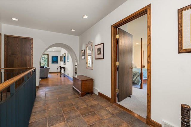 hall with arched walkways, baseboards, recessed lighting, and visible vents