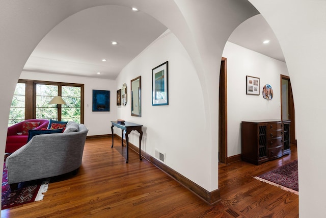 hallway featuring arched walkways, recessed lighting, baseboards, wood finished floors, and visible vents