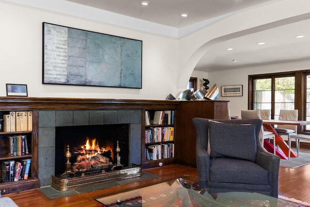 sitting room with arched walkways, a fireplace, recessed lighting, and wood finished floors