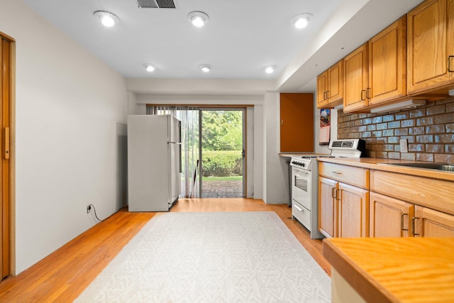 kitchen with white appliances, backsplash, light wood finished floors, and light countertops