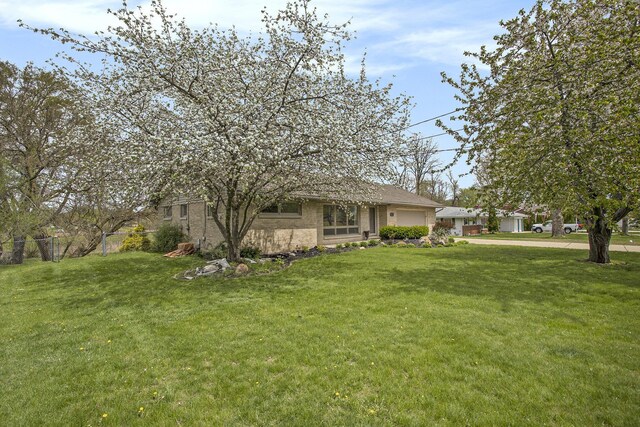 view of yard featuring a garage, fence, and driveway