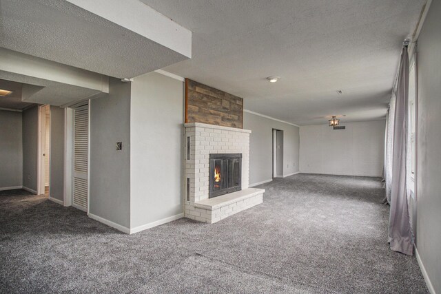 unfurnished living room with a textured ceiling, baseboards, carpet, and a fireplace