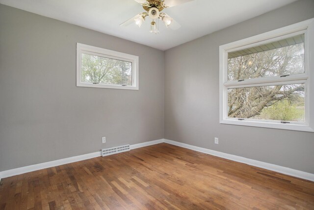 unfurnished room featuring baseboards, a ceiling fan, wood finished floors, and visible vents