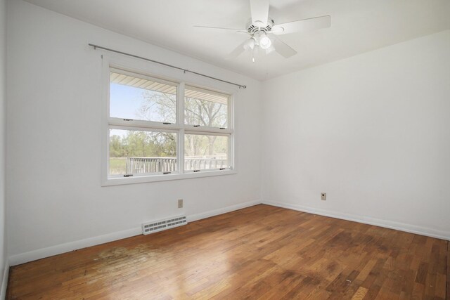 spare room featuring visible vents, a ceiling fan, baseboards, and hardwood / wood-style floors