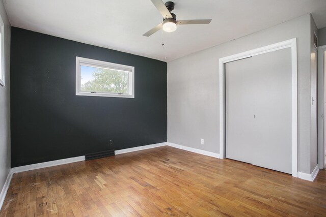 unfurnished bedroom featuring visible vents, baseboards, wood finished floors, and a closet