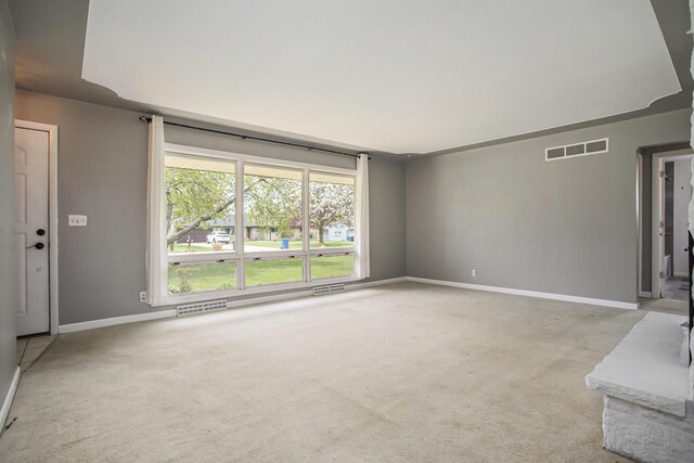 unfurnished living room featuring visible vents, baseboards, and light colored carpet