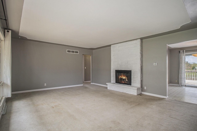 unfurnished living room with baseboards, visible vents, carpet, and a fireplace