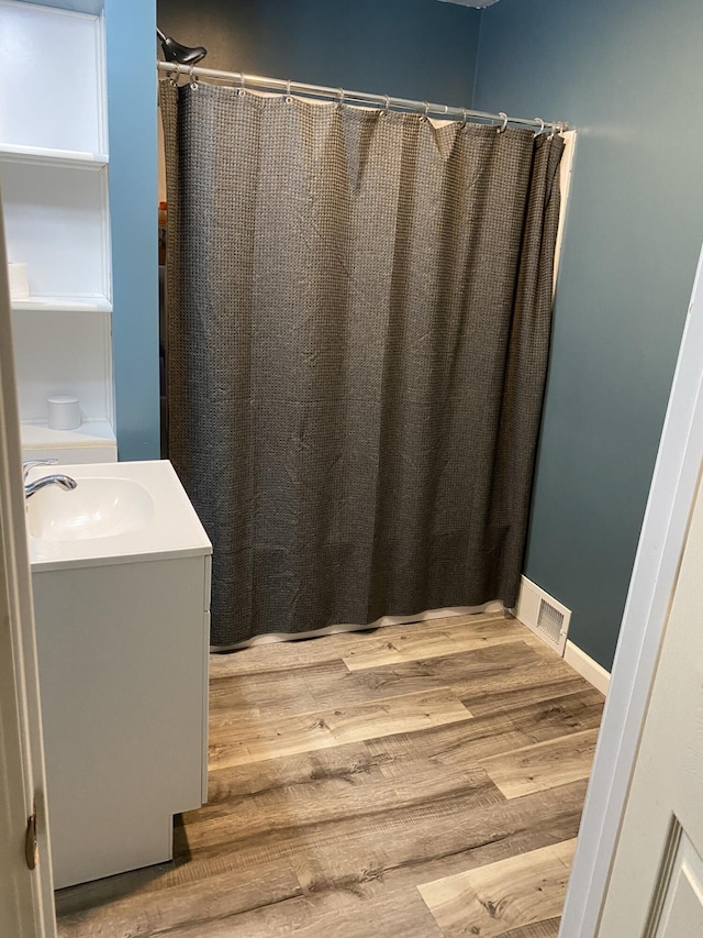 307 N Court St, Stanton, MI 48888 - full bath featuring vanity, a shower with curtain, wood finished floors, and visible vents