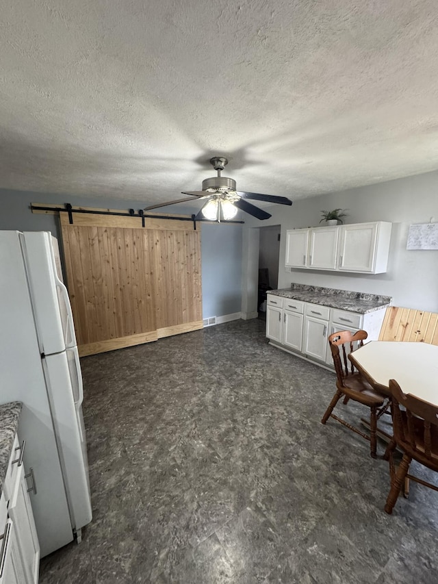 307 N Court St, Stanton, MI 48888 - kitchen featuring ceiling fan, wood walls, baseboards, freestanding refrigerator, and white cabinetry