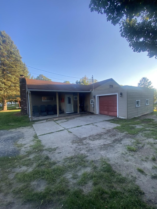 307 N Court St, Stanton, MI 48888 - view of front facade featuring a garage, covered porch, a chimney, and driveway
