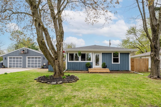 view of front of property featuring a detached garage, fence, concrete driveway, and a front yard