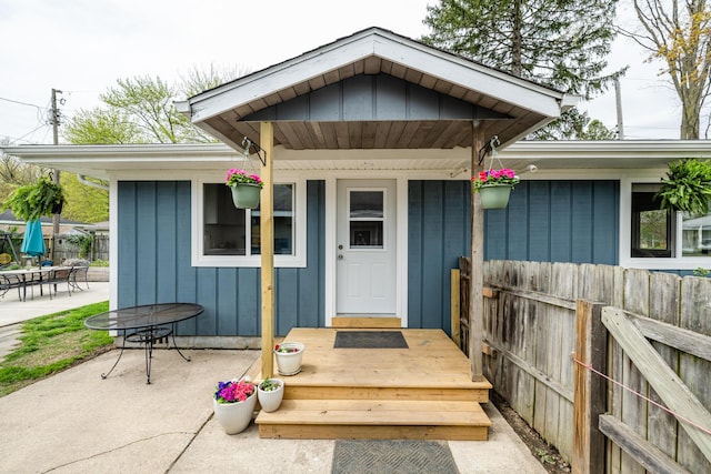 property entrance with board and batten siding, a patio, and fence