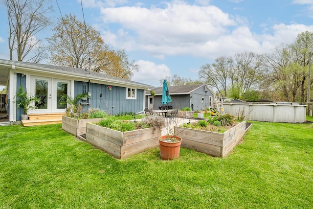 rear view of house featuring french doors, board and batten siding, a yard, and a vegetable garden