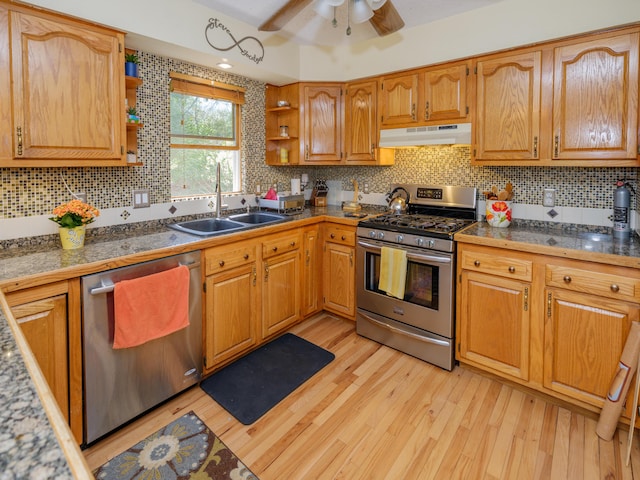kitchen featuring open shelves, appliances with stainless steel finishes, a sink, light wood-style flooring, and under cabinet range hood