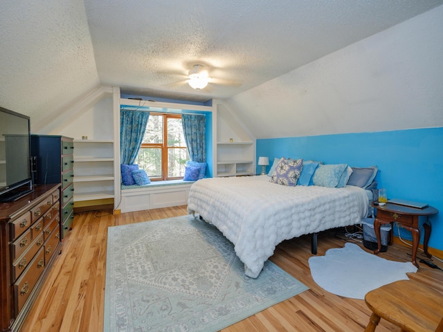 bedroom with light wood-type flooring, a textured ceiling, ceiling fan, and lofted ceiling