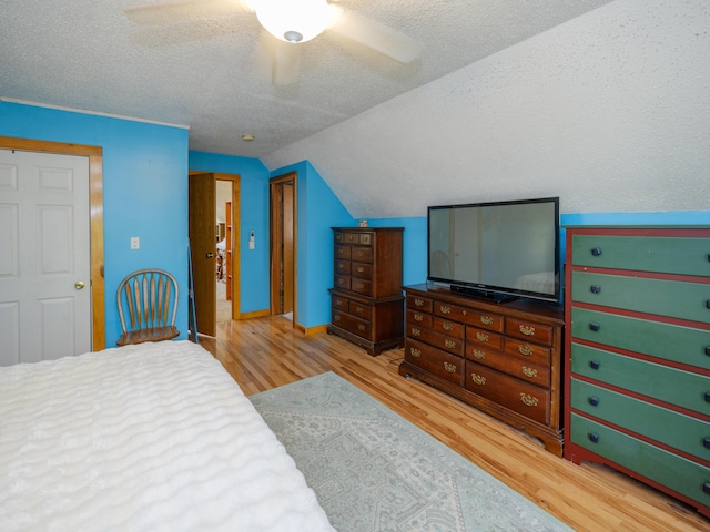 bedroom with a textured ceiling, a ceiling fan, baseboards, wood finished floors, and vaulted ceiling