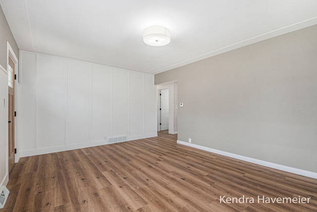 unfurnished room with baseboards, wood finished floors, and visible vents