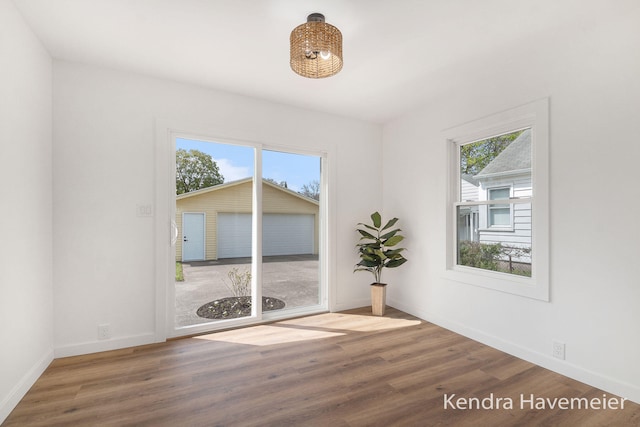 unfurnished room featuring baseboards, wood finished floors, and a healthy amount of sunlight