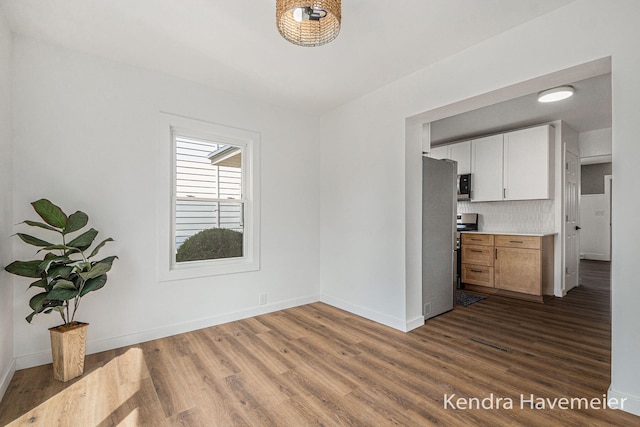 unfurnished dining area with dark wood-type flooring and baseboards