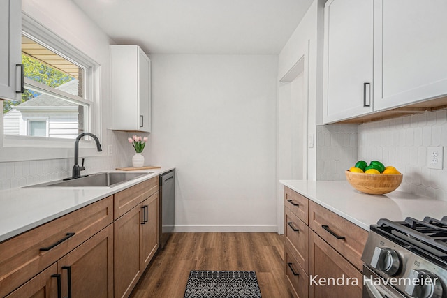 kitchen featuring appliances with stainless steel finishes, a sink, light countertops, decorative backsplash, and dark wood-style floors