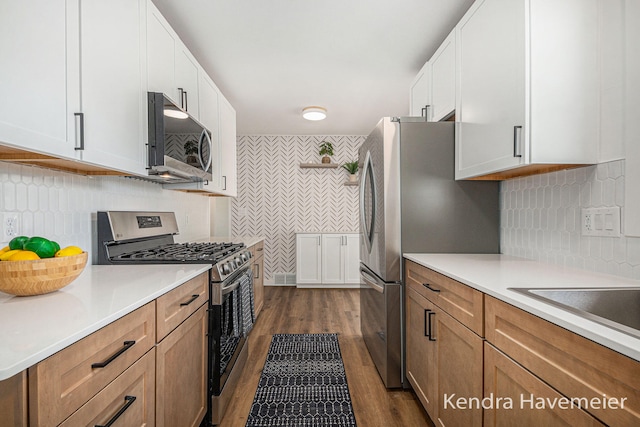 kitchen with white cabinets, appliances with stainless steel finishes, light countertops, tasteful backsplash, and dark wood-style floors