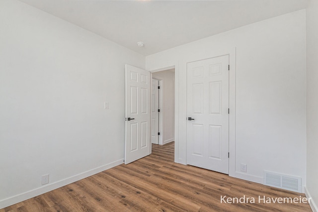 unfurnished bedroom featuring visible vents, baseboards, and wood finished floors