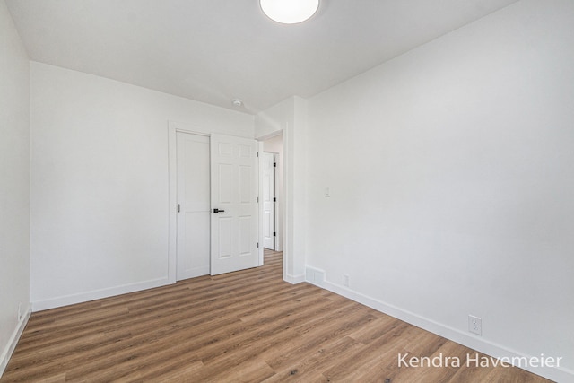 spare room with baseboards and wood finished floors